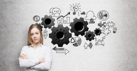 A young business woman with crossed hands. Gears are drawn on the concrete wall. A concept of the business optimisation process.